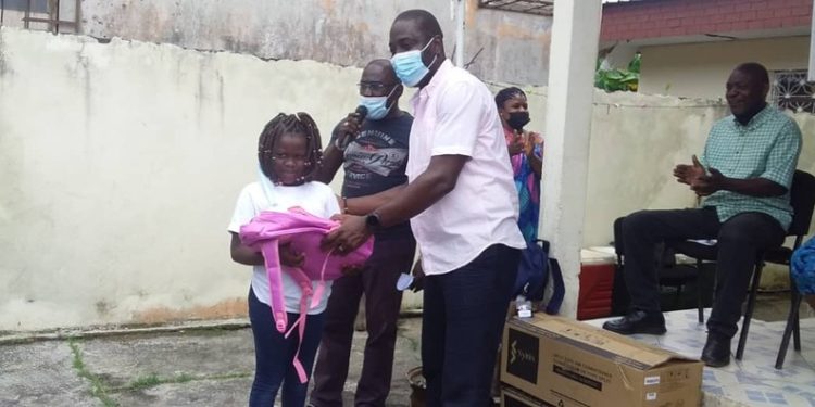 Remise d'un kit scolaire par le donateur Fabrice Moret à un élève