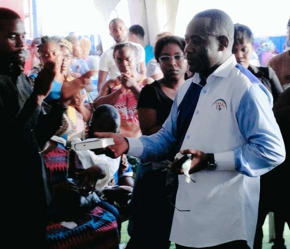 Le Pasteur Alain Roger Boukomba remettant une Bible à un parent au Port Môle